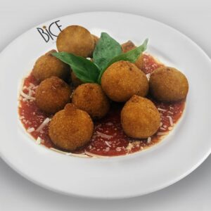 Arancini di spinaci e parmigiano dorés, croustillants à l’extérieur et crémeux à l’intérieur, servis sur roquette