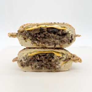 Panino au steak avec cheddar, sauce Bombe maison, oignons caramélisés et champignons