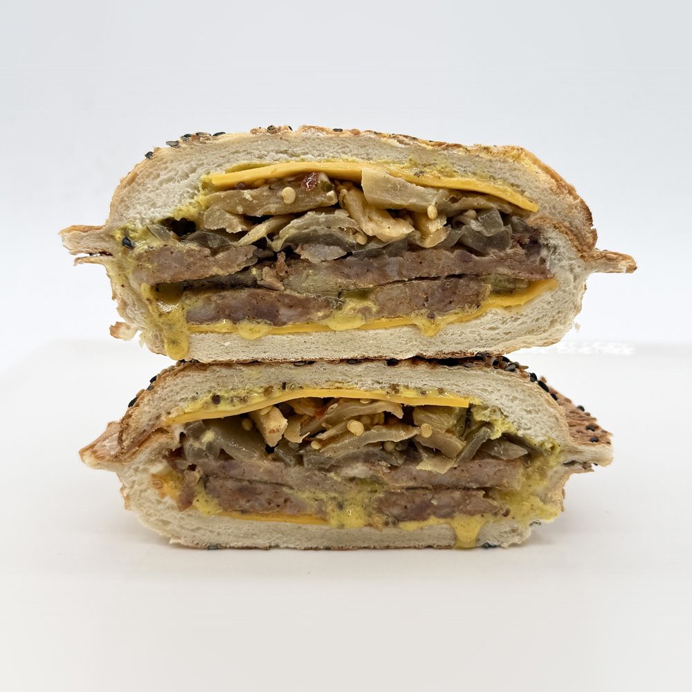 Saucisse italienne au panino Saucisse italienne servie dans un pain panino au sésame avec cheddar, moutarde au miel, oignons caramélisés et aubergines