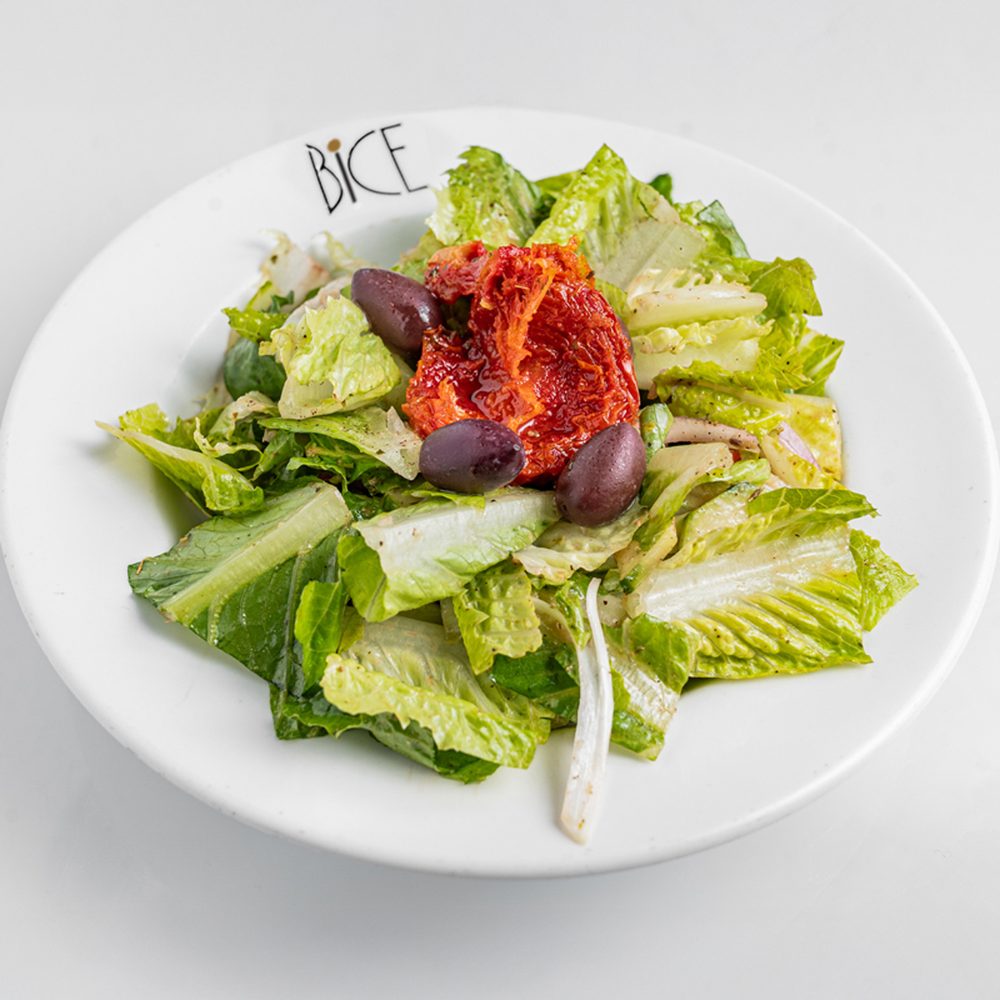Salade maison signature Salade maison signature avec laitue romaine, tomates cerises, concombres et oignons rouges